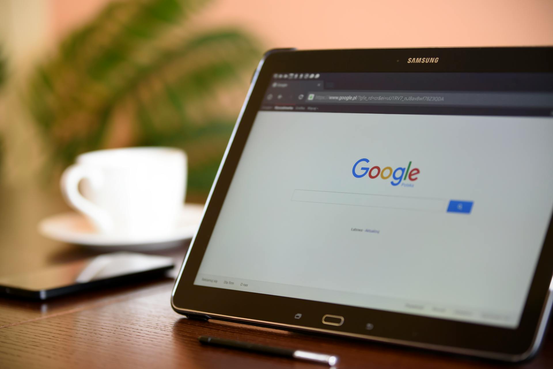 Tablet showing the Google search page beside a cup of coffee