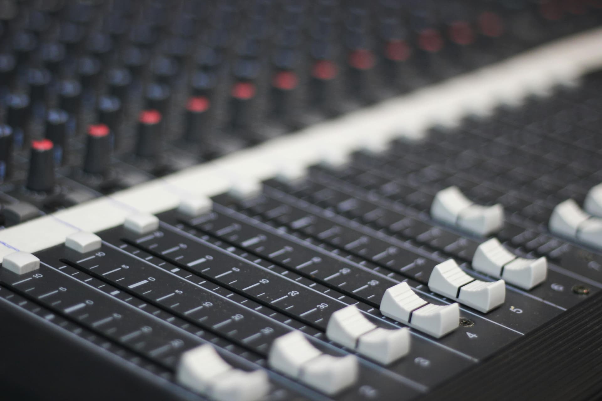 Close-up of sliders and knobs on an audio mixing desk