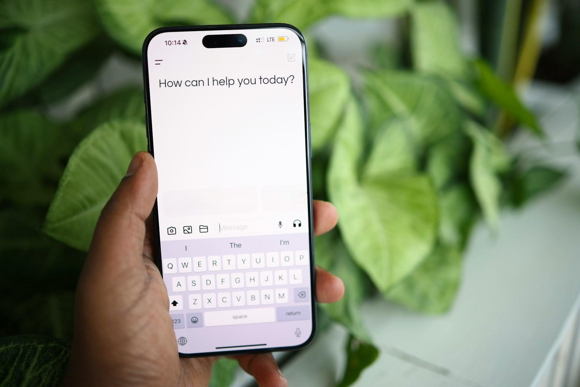 Hand holding a phone showing a chat app asking how can I help you today