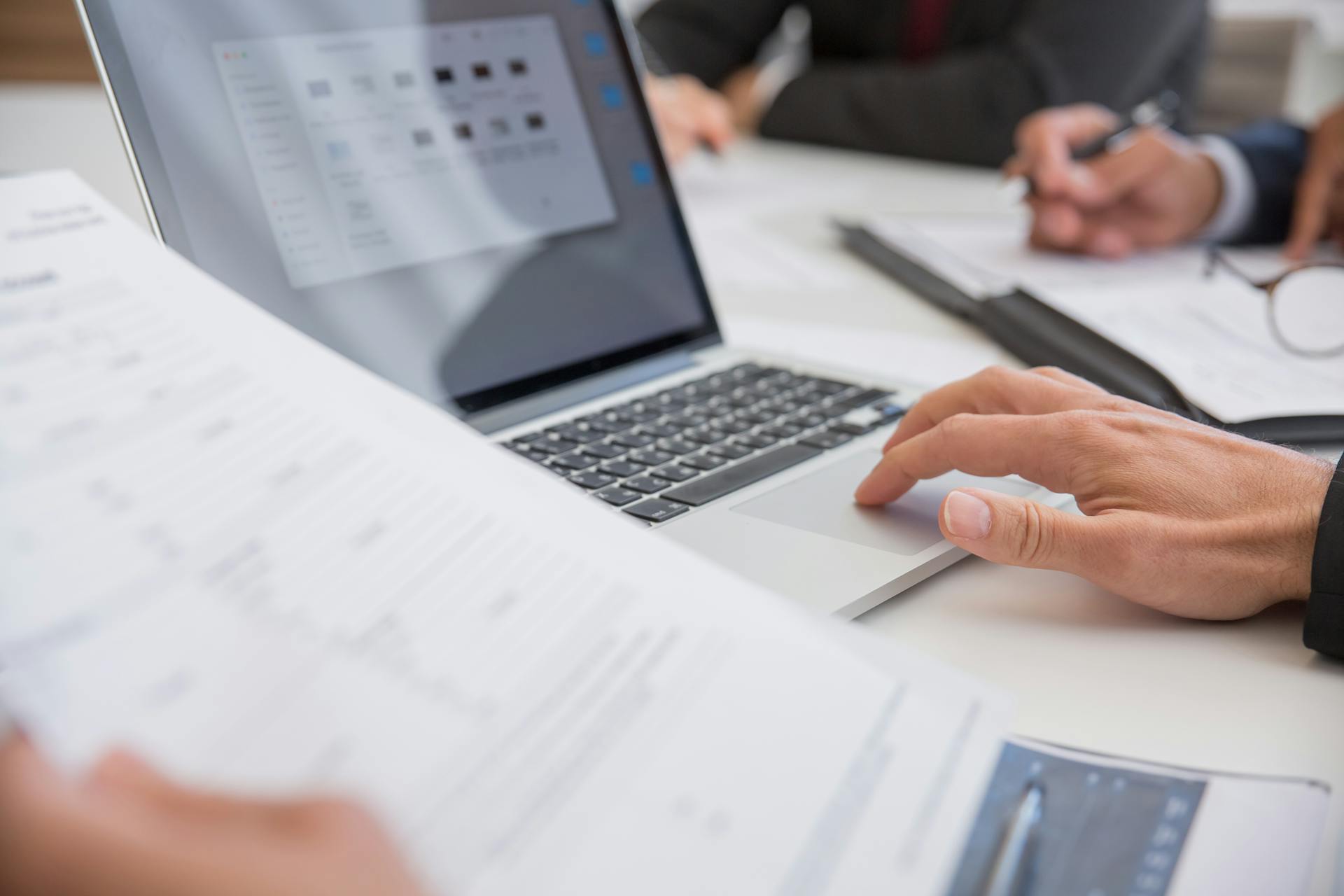 Professionals reviewing documents beside a laptop in a meeting