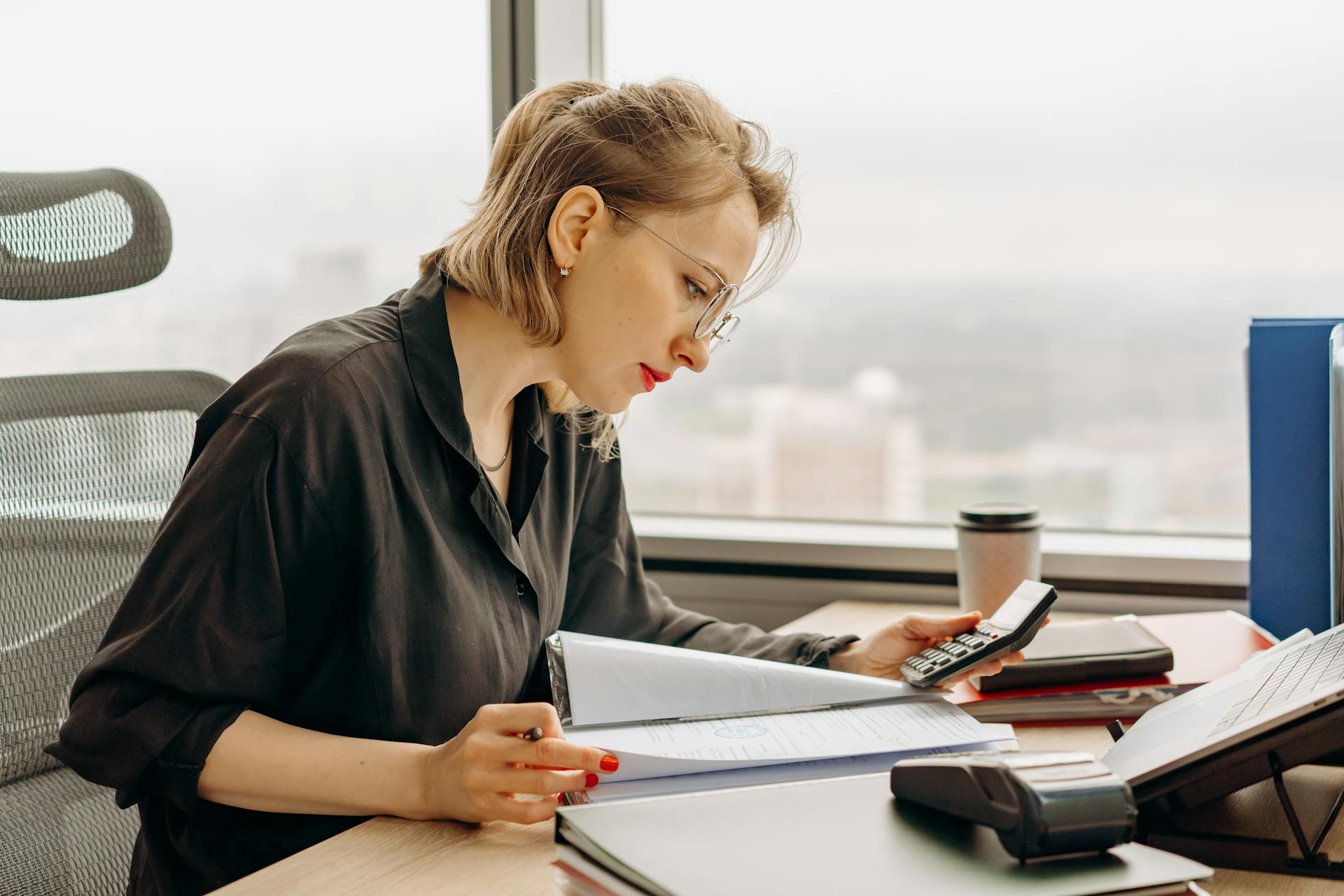 Accountant checking figures with a calculator and a folder of papers